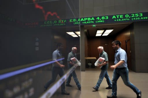 Employees pass an electronic display at the Athens stock exchange. Despite making progress, the eurozone debt crisis remains unsolved and, in a repeat of last summer, could still bring nasty surprises to global stock markets in July and August, analysts said