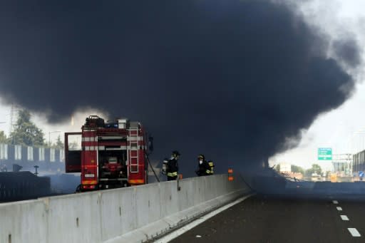 Firefighters work at the scene where a tanker truck exploded on a motorway just outside Bologna, northern Italy, on August 6, 2018