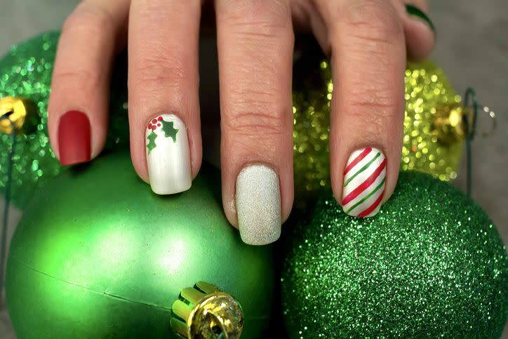 holly berry nail art design on hands with nails painted red and white and green