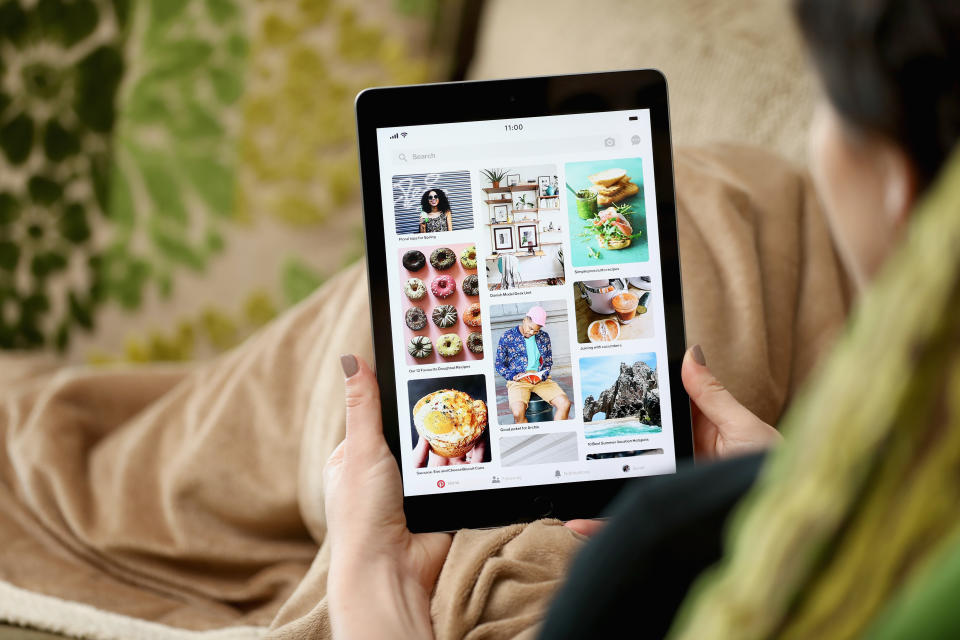 A woman on a couch looks at Pinterest's app on an iPad.