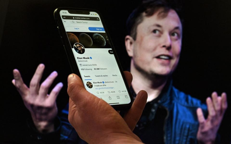 ) In this file photo illustration, a phone screen displays the Twitter account of Elon Musk with a photo of him shown in the background, on April 14, 202 - OLIVIER DOULIERY/ AFP