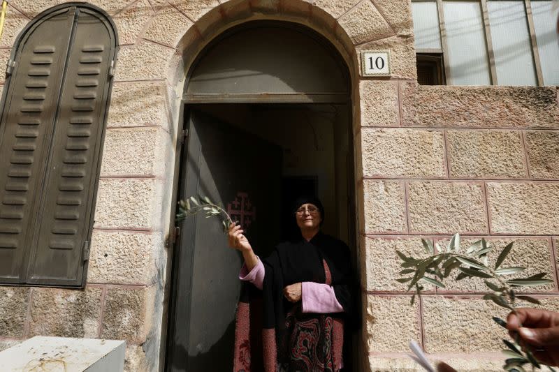 A woman holds an olive branch she received from members of the Latin Patriarchate as they distributed the branches to Christian residents on Palm Sunday, during Holy Week amid the coronavirus disease (COVID-19) outbreak, in Jerusalem's Old City