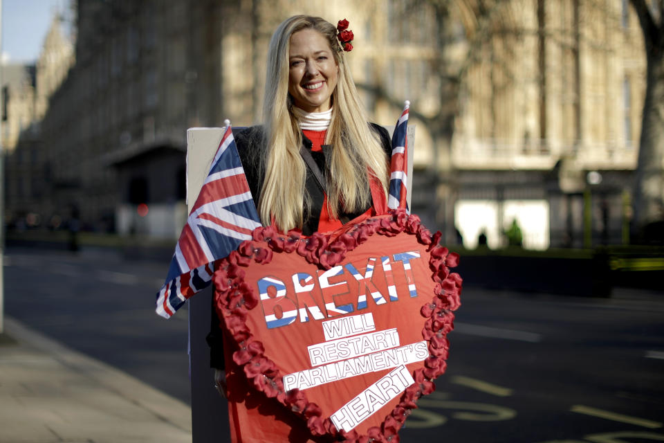 Leave the European Union supporter Belinda Delucy, aged 42 from London, poses for photographs backdropped by the Houses of Parliament in London, Thursday, Feb. 14, 2019. Belinda believes leaving the EU with no-deal and then the EU making Britain a better offer after Brexit would the best way forward. Some demonstrators have been coming to the grounds outside parliament for days, weeks or even months, to make their case as to whether Britain should stay inside the European Union or leave on March 29, as planned.(AP Photo/Matt Dunham)