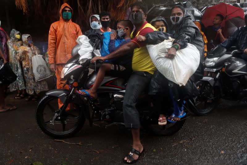 A man rides a bike carrying his family and belongings during an evacuation of a slum off the coast of the Arabian sea as cyclone Nisarga makes its landfall, in Mumbai