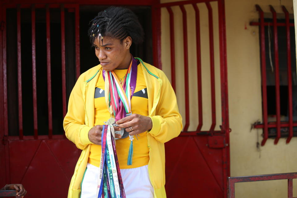 Guinean wrestler Fatoumata Yarie Camara holds past credentials and medals at her house in Conakry, Guinea, Monday July 19, 2021. A West African wrestler's dream of competing in the Olympics has come down to a plane ticket. Fatoumata Yarie Camara is the only Guinean athlete to qualify for these Games. She was ready for Tokyo, but confusion over travel reigned for weeks. The 25-year-old and her family can't afford it. Guinean officials promised a ticket, but at the last minute announced a withdrawal from the Olympics over COVID-19 concerns. Under international pressure, Guinea reversed its decision. (AP Photo/Youssouf Bah)