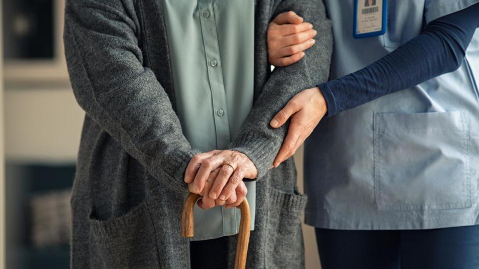 Nurse assisting senior with walking cane