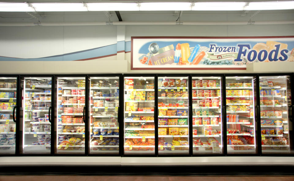 Aisle with a variety of frozen food items displayed in glass door freezers under a "Frozen Foods" sign