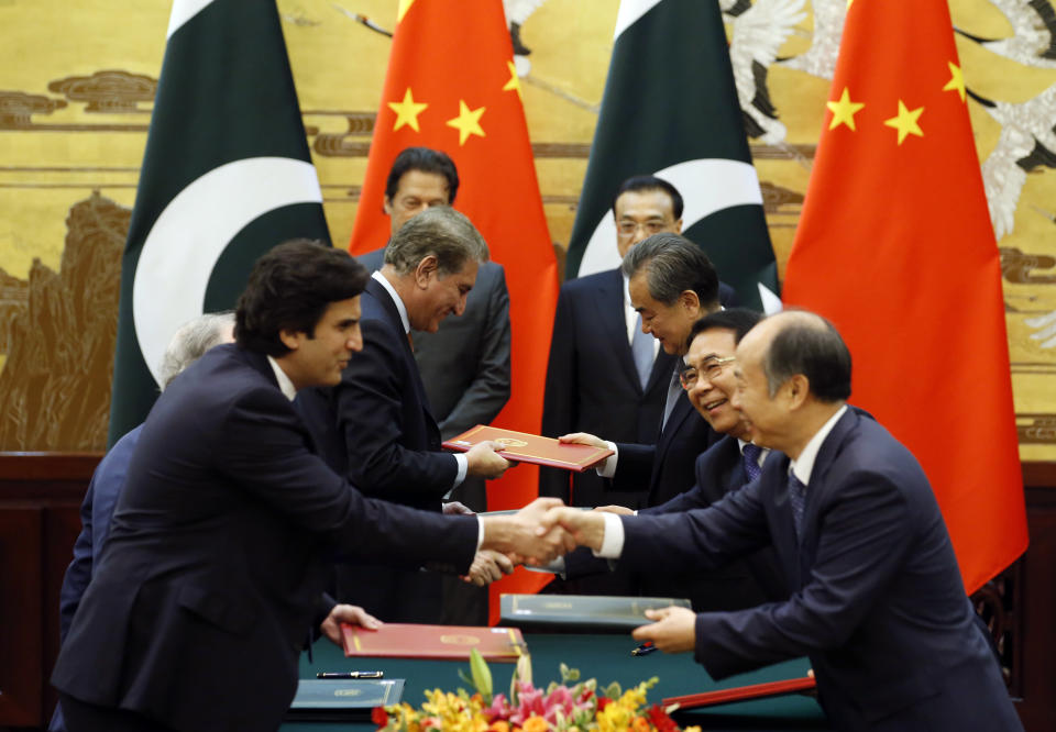 Officials change documents as Pakistani Prime Minister Imran Khan, rear left, and China's Premier Li Keqiang, rear right, attend a signing ceremony at the Great Hall of the People in Beijing Saturday, Nov. 3, 2018. (Jason Lee/Pool Photo via AP)