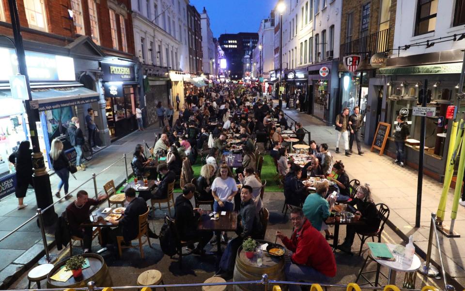 People eating on restaurant tables placed outside on Old Compton St in Soho, London, - Yui Mok/PA Wire