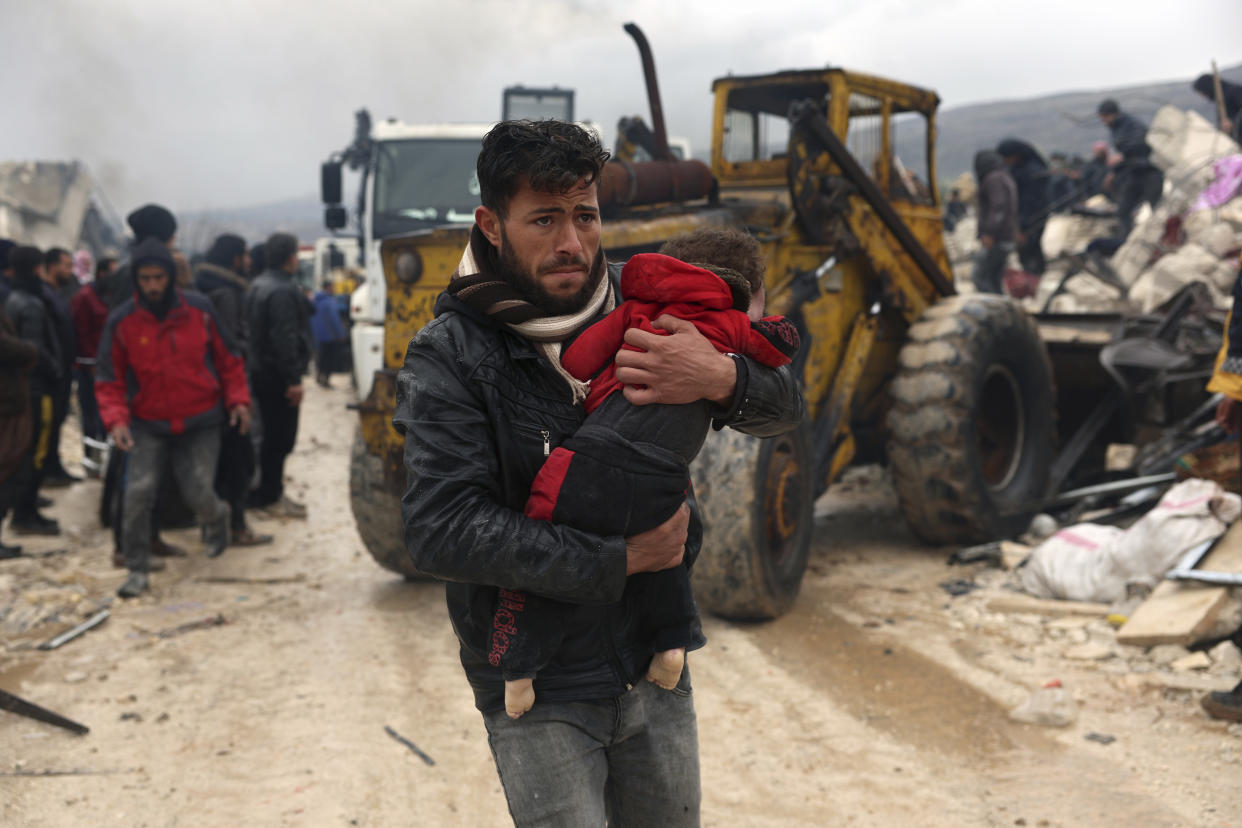 A man carrying a child in the village of Besnia in Syria.