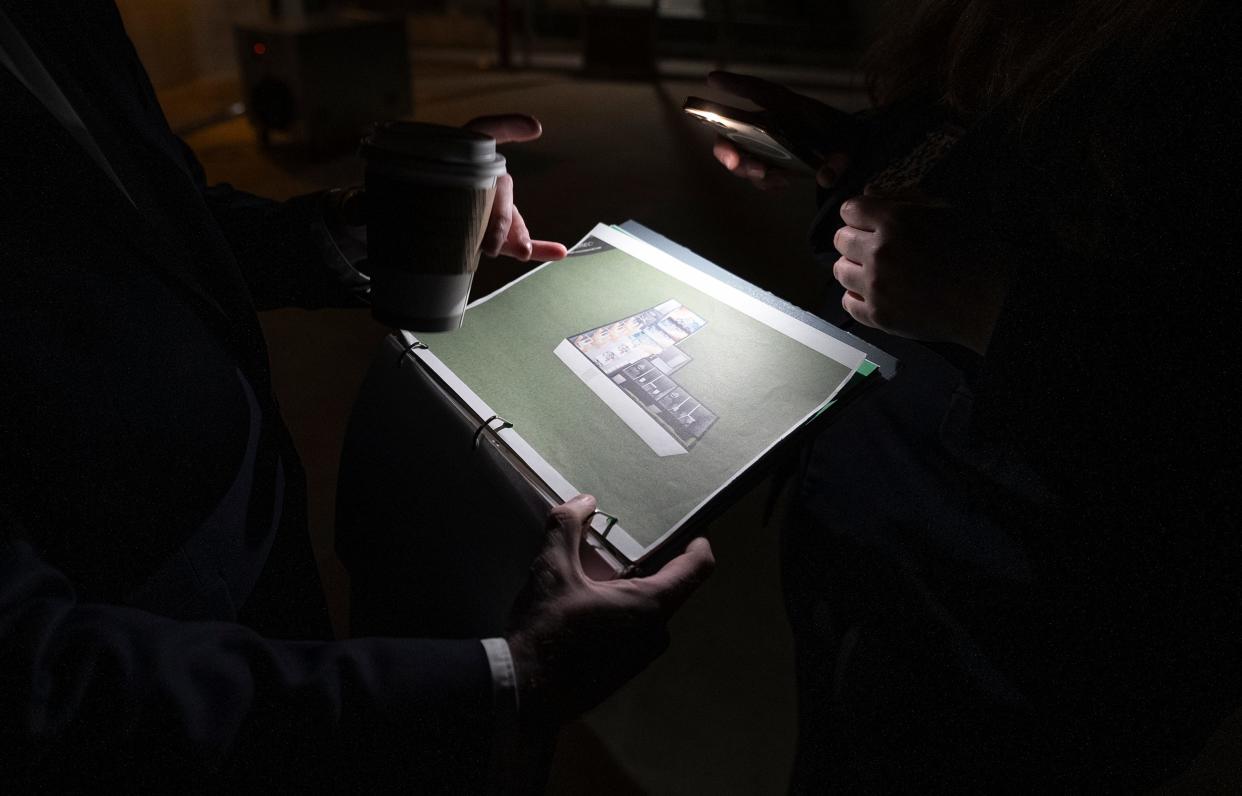 Tora Bonnier uses her cellphone flashlight to illuminate plans for the new nightclub space in the basement.