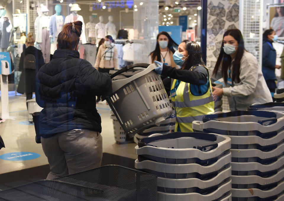 Early morning shoppers take a shopping basket from a member of staff as they enter the Primark store, Birmingham, which has reopened to customers as England takes another step back towards normality with the further easing of lockdown restrictions. Picture date: Monday April 12, 2021.