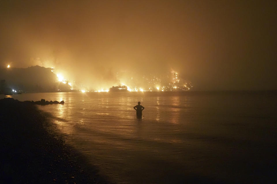 A man watches the flames as a wildfire approaches Kochyli beach near the village of Limni, Greece, on the island of Evia, about 160 kilometers (100 miles) north of Athens, late Friday, Aug. 6, 2021, as wildfires raged through Greece and Turkey. (AP Photo/Thodoris Nikolaou)