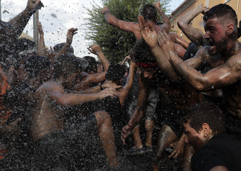 In this photo taken on Friday, Sept. 6, 2019, people painted with black grease celebrate during the traditional festivities of the Cascamorras festival in Baza, Spain. During the Cascamorras Festival, and according to an ancient tradition, participants throw black paint over each other for several hours every September 6 in the small town of Baza, in the southern province of Granada. The "Cascamorras" represents a thief who attempted to steal a religious image from a local church. People try to stop him, chasing him and throwing black paint as they run through the streets. (AP Photo/Manu Fernandez)