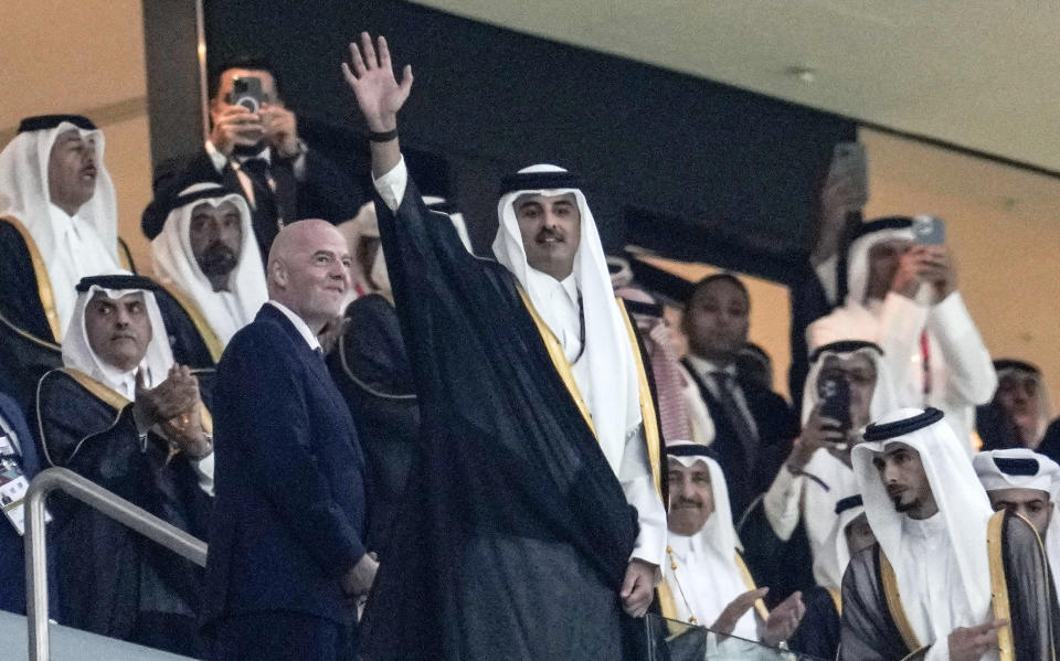Emir of Qatar Tamim bin Hamad Al Thani waves to the crowd beside FIFA President Giovanni Infantino, left, prior the World Cup, group A soccer match between Qatar and Ecuador at the Al Bayt Stadium in Al Khor, Sunday, Nov. 20, 2022. (AP Photo/Natacha Pisarenko)