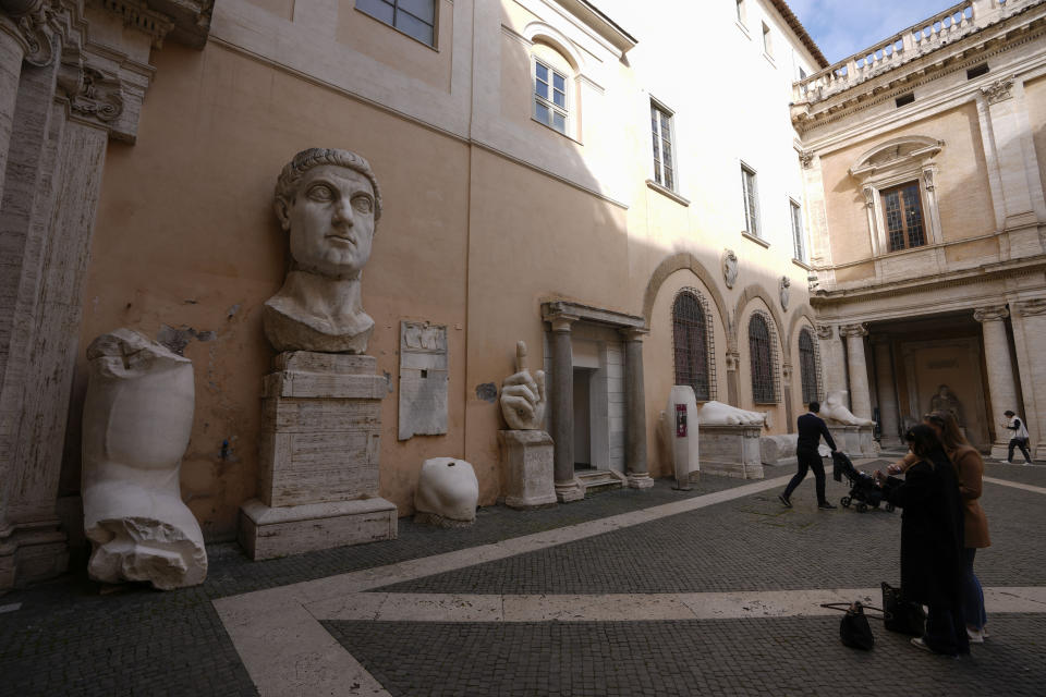 People admire the surviving portions of the statue of Roman emperor Constantine the Great (c. 280–337) commissioned for himself after 312 AD, on display in a courtyard of the Capitoline Museums, in Rome, Tuesday, Feb. 6, 2024. The museum unveiled in one of its side gardens a massive, 13-meter (yard) replica of the statue built using 3D technology from scans of the nine giant original marble body parts that remain. (AP Photo/Andrew Medichini)