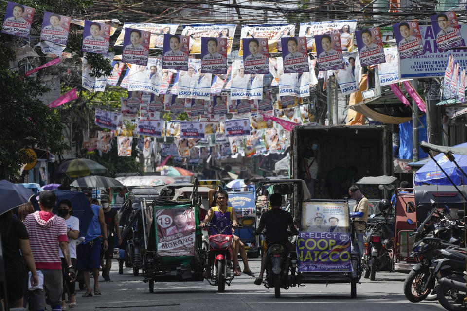 Residents pass by election campaign posters near a polling center in Manila, Philippines, Friday, May 6, 2022. The son of the late dictator Ferdinand Marcos Sr., Ferdinand Marcos Jr. and the current Vice-President Leni Robredo continue to lead against other presidential candidates as the country prepares to vote for its new leader next week. (AP Photo/Aaron Favila)