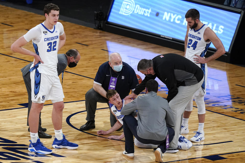 Creighton's Ryan Kalkbrenner (32) and Mitch Ballock (24) watch as coach Greg McDermott checks on Alex O'Connell, who was hurt during the first half of the team's NCAA college basketball game against Butler in the Big East men's tournament Thursday, March 11, 2021, in New York. (AP Photo/Frank Franklin II)