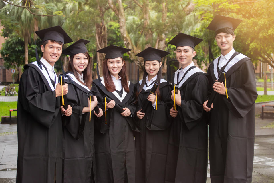 Group of young university students with graduation gowns feeling excited and pride posted for a group photo