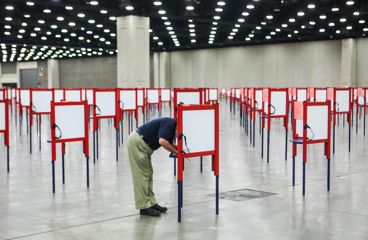 A man stands at a voting booth surrounded by many empty voting booths during early voting in Kentucky