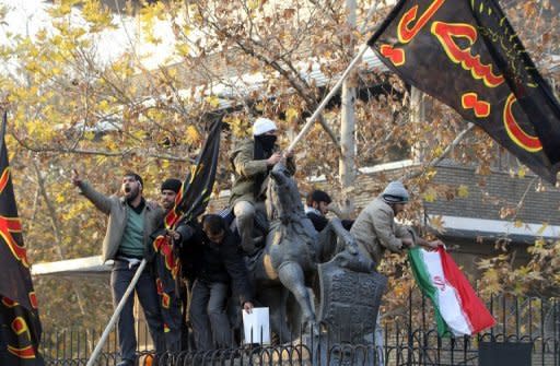 Iranian protesters stand on the wall of the British embassy in Tehran on November 29. Iran's regime has started to distance itself from militant protesters who stormed Britain's embassy, after seemingly being caught off balance by the retaliatory closure of its mission in London