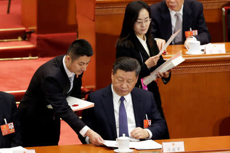 An attendant hands out ballot paper to Chinese President Xi Jinping at the third plenary session of the National People's Congress (NPC), where delegates will vote on a constitutional amendment lifting presidential term limits, at the Great Hall of the People in Beijing, China March 11, 2018. REUTERS/Jason Lee