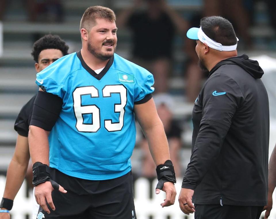 Carolina Panthers center Austin Corbett, center, speaks to a coach after snapping the ball to quarterback Bryce Young during training camp practice on Thursday, July 25, 2024.