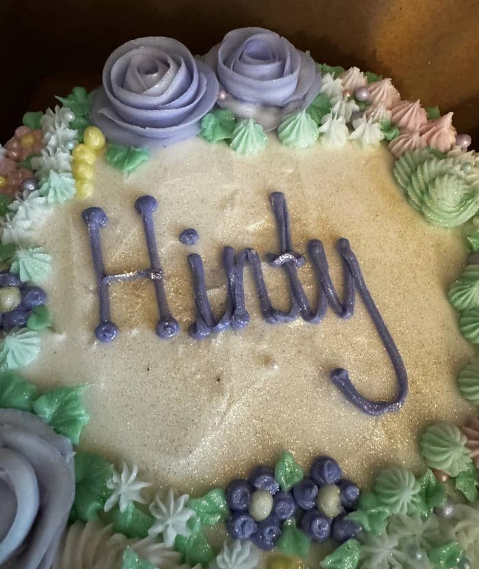 Decorative cake with "Hindy" written in icing, adorned with icing flowers and details