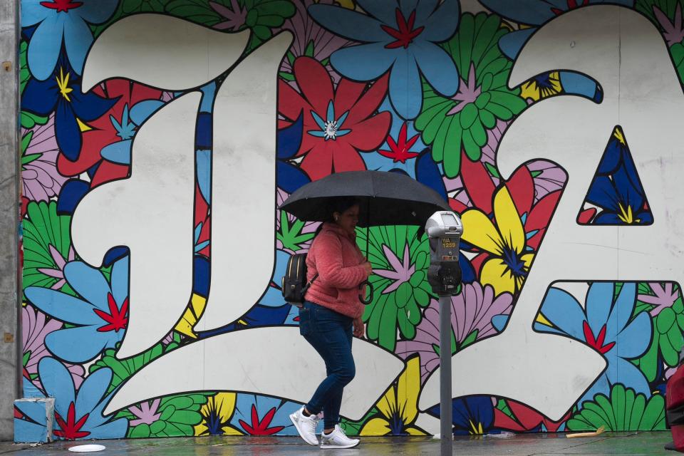 A woman walks with an umbrella in Los Angeles on 19 February 2024 (AP)