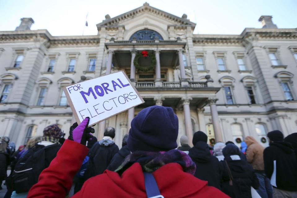 A protester holds up a sign as a group demonstrates in freezing temperatures at the Statehouse, ahead of New Jersey's Electoral College, Monday, Dec. 19, 2016, in Trenton, N.J. (AP Photo/Mel Evans)