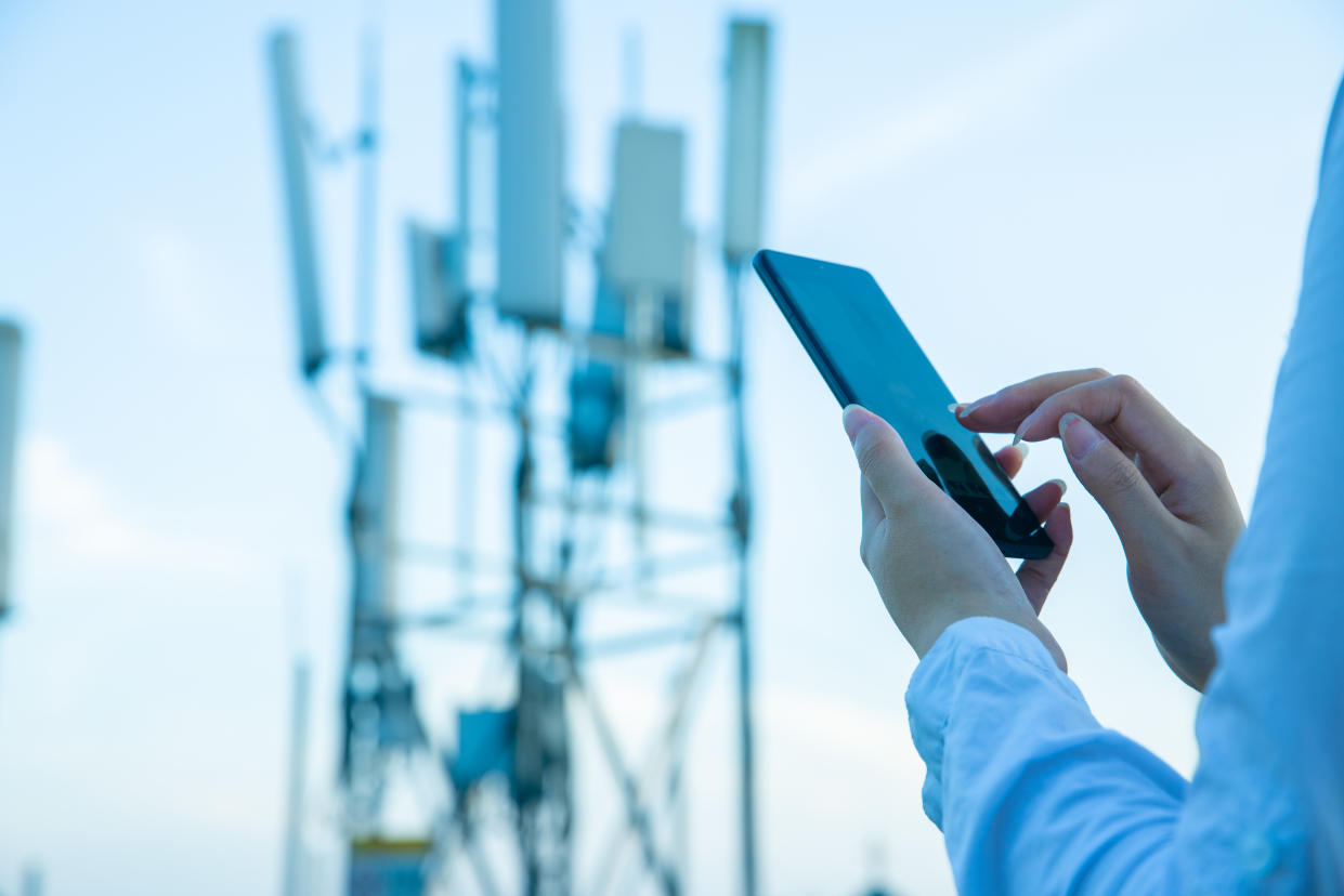 Human hand using mobile phone near 4G,5G communications tower