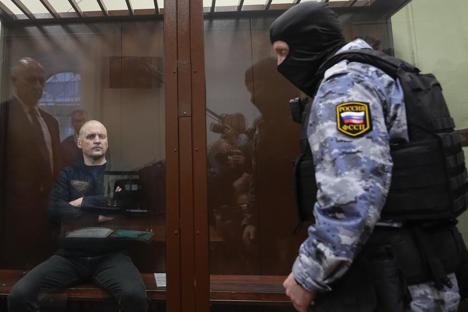 Sergei Udaltsov, Russian left-wing political activist, left, sits behind a glass in a cage in a courtroom in Moscow, Russia, Friday, Jan. 12, 2024. A Russian state news agency says a Russian court has ordered that a pro-war activist and critic of President Vladimir Putin be remanded into custody until Feb. 15. That's when Sergei Udaltsov will stand trial for charges of "justifying terrorism." (AP Photo/Alexander Zemlianichenko)