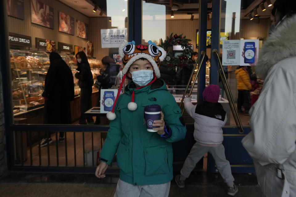 A child walks out with a beverage from a bakery as visitors return to a mall with shops re-opening for business as restrictions are eased in Beijing, Saturday, Dec. 3, 2022. Chinese authorities on Saturday announced a further easing of COVID-19 curbs with major cities such as Shenzhen and Beijing no longer requiring negative tests to take public transport. (AP Photo/Ng Han Guan)