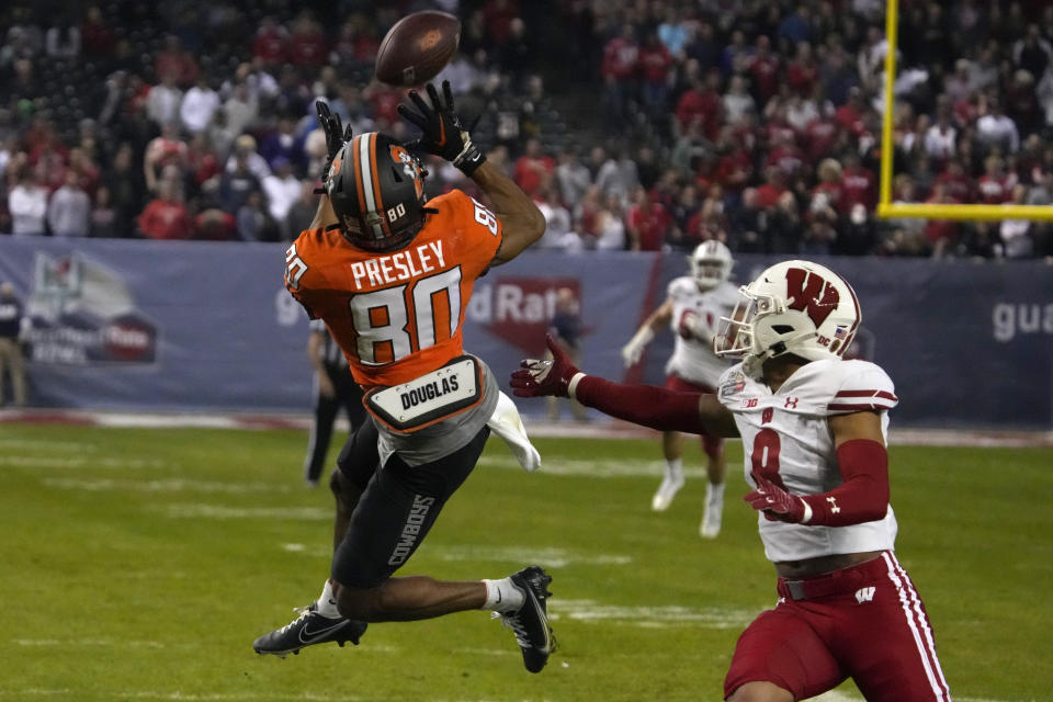 Oklahoma State wide receiver Brennan Presley (80) makes the catch in front of Wisconsin cornerback Avyonne Jones during the second half of the Guaranteed Rate Bowl NCAA college football game Tuesday, Dec. 27, 2022, in Phoenix. Wisconsin 24-17. (AP Photo/Rick Scuteri)