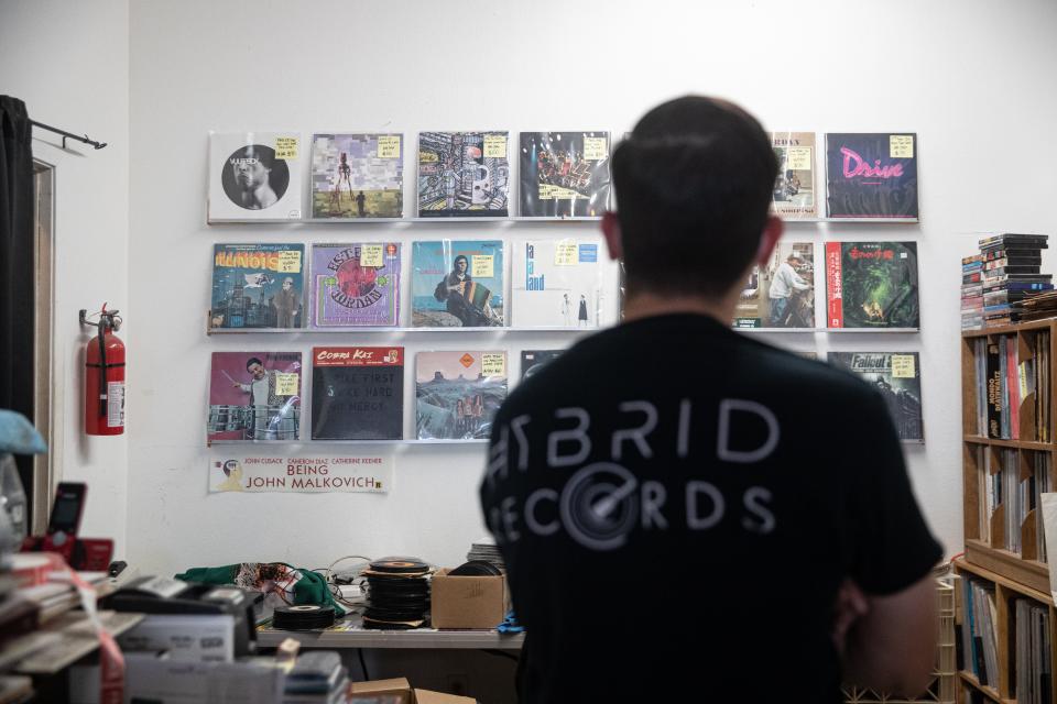 Carlos Cooper, owner of Hybrid Records at 4233 S. Alameda St., in Corpus Christi, looks at a wall of records behind the checkout counter of his store, Nov. 5, 2021. 
