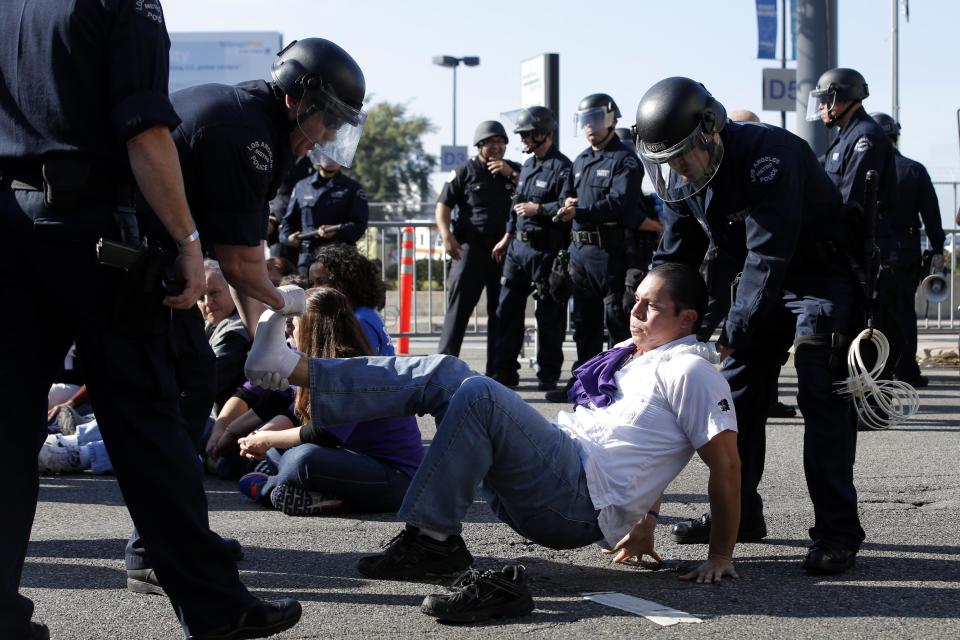 Police officers arrest Ron Gochez during a protest in Los Angeles, Wednesday, Nov. 21, 2012. Hundreds of workers at Los Angeles International Airport marched Wednesday near the entrance to Los Angeles International Airport, where Thanksgiving travelers were warned to arrive early in case of traffic snarls. (AP Photo/Jae C. Hong)