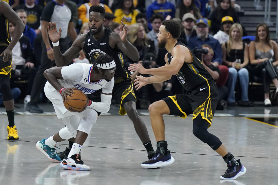 Los Angeles Clippers guard Reggie Jackson, front left, is defended by Golden State Warriors forward JaMychal Green, back left, and guard Stephen Curry during the first half of an NBA basketball game in San Francisco, Wednesday, Nov. 23, 2022. (AP Photo/Jeff Chiu)