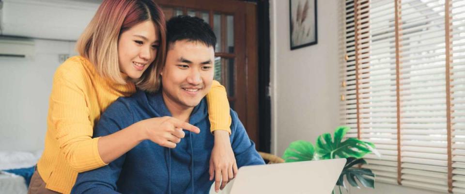 Young couple happy looking at laptop