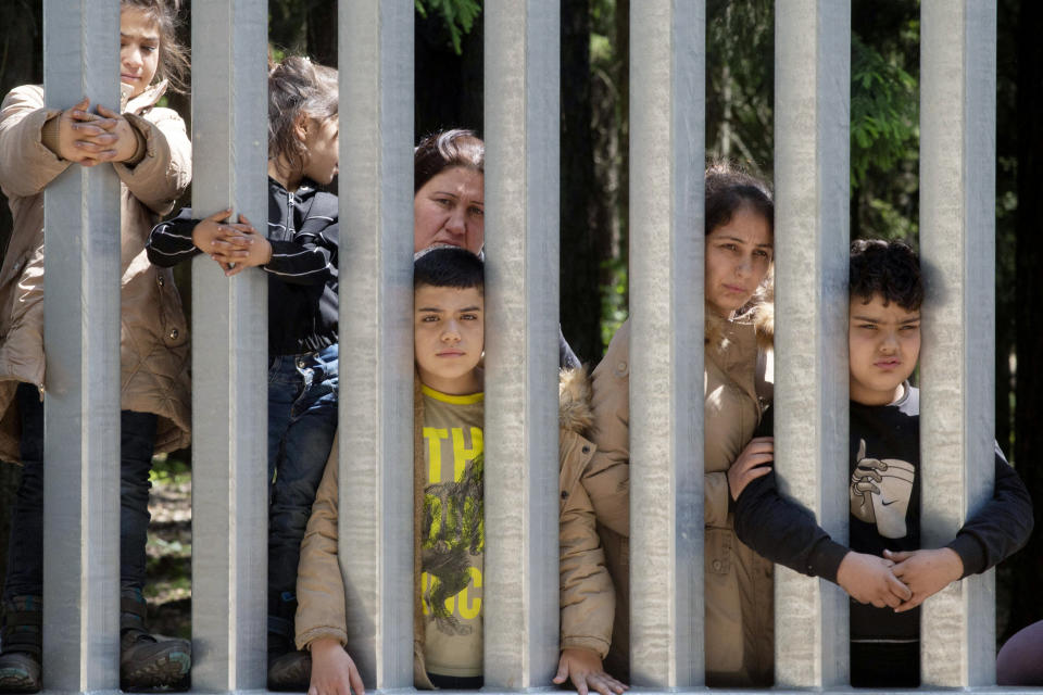 Members of a group of some 30 migrants seeking asylum are seen in Bialowieza, Poland, on Sunday, 28 May 2023 across a wall that Poland has built on its border with Belarus to stop massive migrant pressure. The group has remained stuck at the spot for three days, according to human rights activists. (AP Photo/Agnieszka Sadowska)