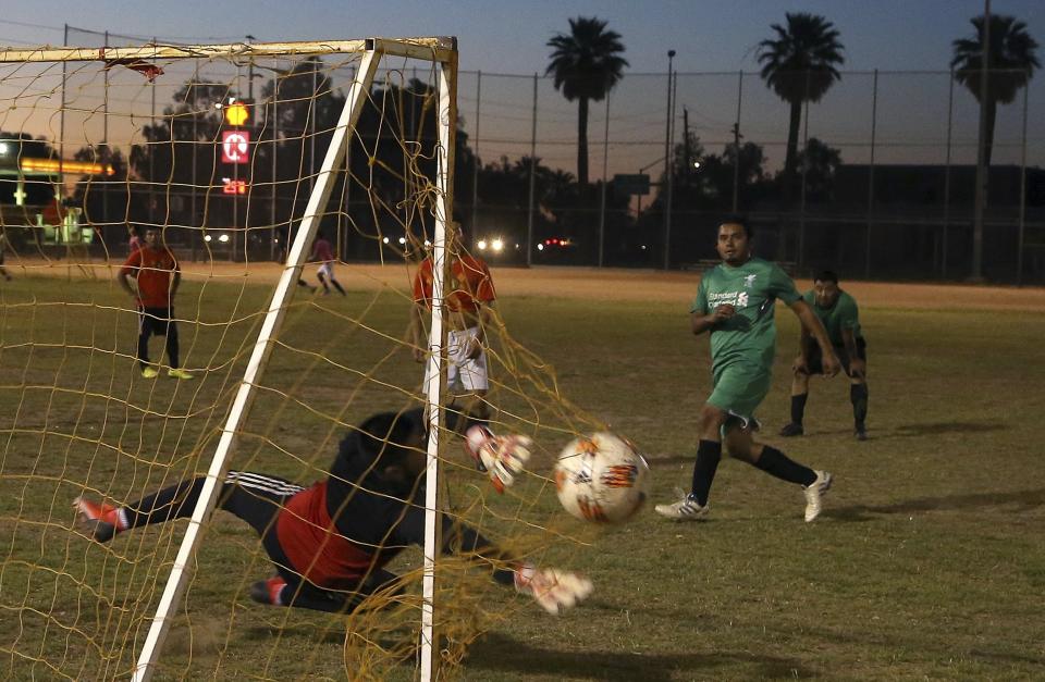 A member of the Michoacan team, right, scores a goal at a Maya Chapin soccer league game Wednesday, April 17, 2019, in Phoenix. (AP Photo/Ross D. Franklin)