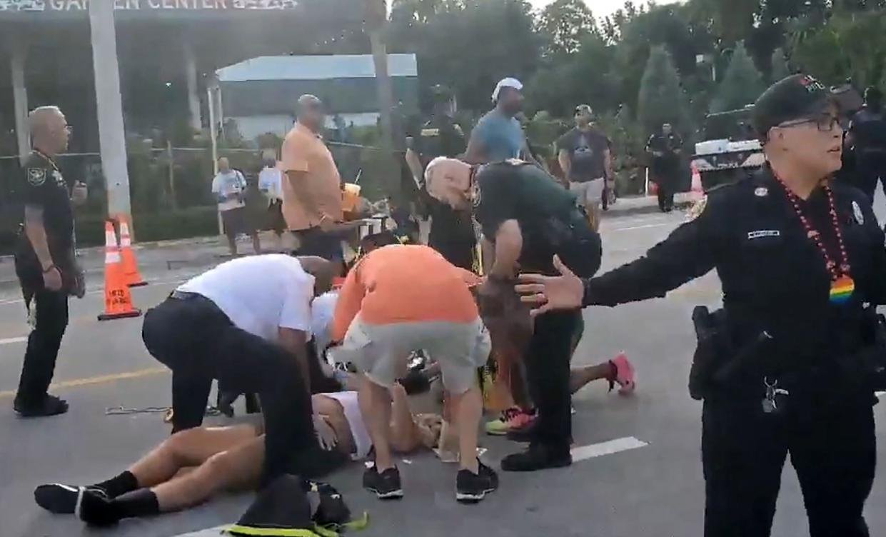 This handout video grab courtesy of @pinto_spears shows police officers and others assisting two people laying on the ground after being hit by a pickup truck during a Pride parade in Wilton Manors, near Fort Lauderdale, Florida on June 19, 2021. - The driver of a pickup truck slammed into a crowd gathering for a Pride parade Saturday in south Florida, killing at least one man, US media reports said. It was not immediately clear if this was a deliberate assault. The incident happened at the start of the LGBTQ parade in the town of Wilton Manors near Ft. Lauderdale. The driver was later taken into custody.