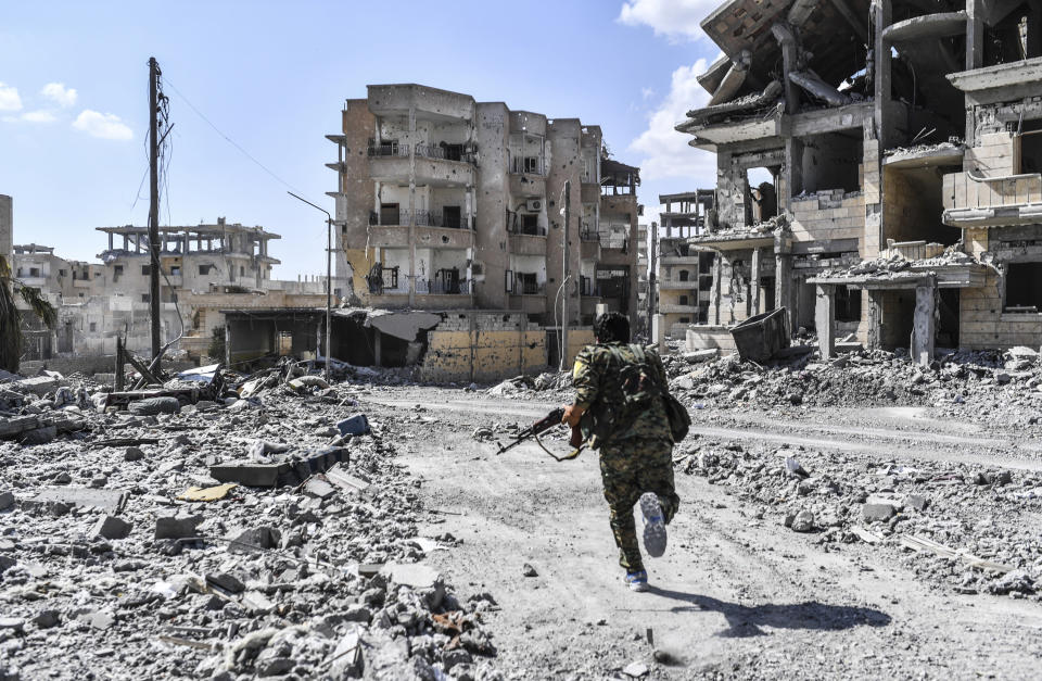 A member of the Syrian Democratic Forces takes cover from sniper shots near the central hospital of Raqqa on Oct. 1. (Photo: BULENT KILIC via Getty Images)