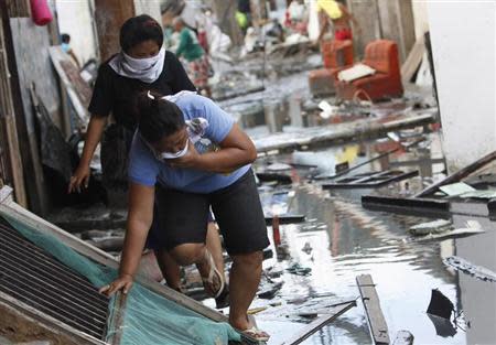 People carefully avoid the dirty water along an alley as they leave their makeshift homes, after super typhoon Haiyan battered Tacloban City, in central Philippines November 13, 2013. REUTERS/Edgar Su