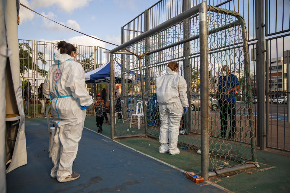 Israeli healthcare workers speak with a man who wants to test himself for the coronavirus at a testing center for migrants in Tel Aviv, Israel, Monday, July 6, 2020. Israel is reimposing a series of restrictions after seeing a surge of coronavirus infections in recent weeks. (AP Photo/Oded Balilty)