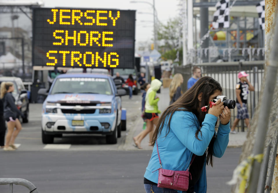 Angelina Zuzuro, 16, of Denville, takes photos near a sign in Seaside Heights, N.J., Saturday, May 18, 2013. The boardwalks are back, and so are most of the beaches, even if some are a little thinner this year. The smell of funnel cakes, french fries and pizza will mingle with the salt air, and the screech of seagulls will be heard. But so will the thwack of hammers repairing what can be fixed and the roar of bulldozers and backhoes tearing down what can’t. Welcome to Summer 2013 at the Jersey shore, the first since Superstorm Sandy pummeled the coast and upended hundreds of thousands of lives. (AP Photo/Mel Evans)