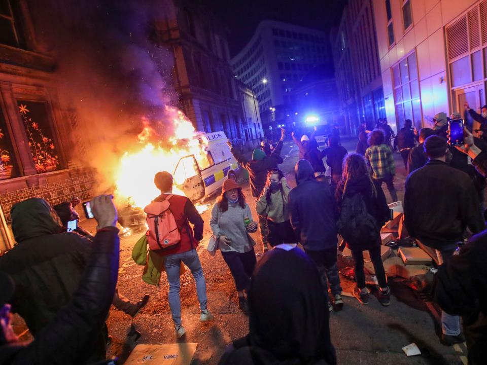 Demonstrators in Bristol stand near a burning police vehicle during a protest against the proposed policing bill (Reuters/Peter Cziborra)