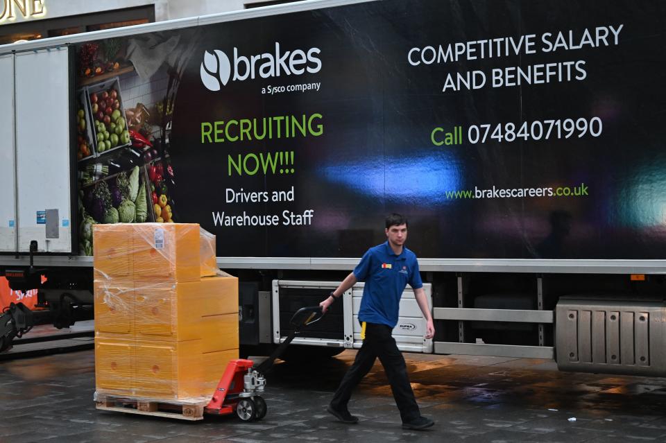 A worker delivers goods from a lorry that is advertising driving and warehouse vacancies to a business in Leicester Square in London on October 13, 2021. - A shortfall in HGV drivers has sparked fuel shortages and fears of empty shelves in supermarkets over Christmas. (Photo by JUSTIN TALLIS / AFP) (Photo by JUSTIN TALLIS/AFP via Getty Images)