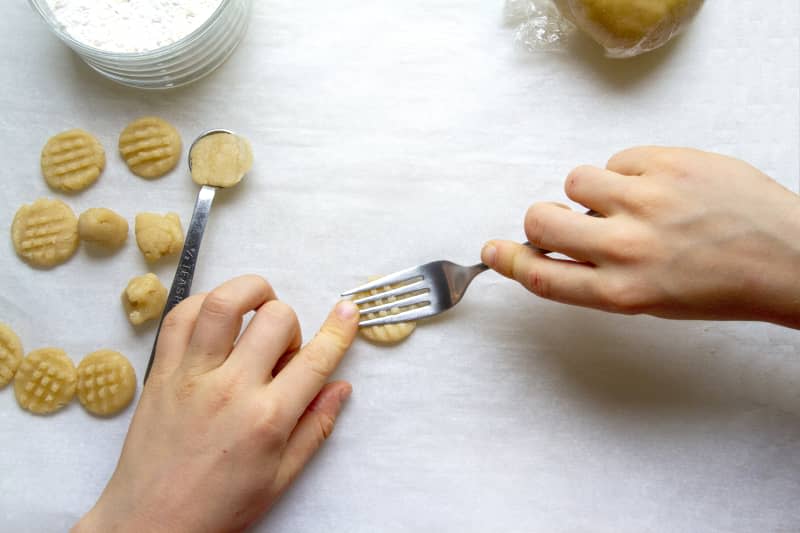 someone adding crosshatching to cookies with a fork