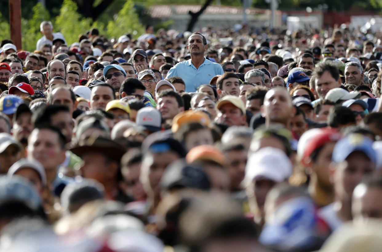 ARCHIVO – En esta foto de archivo del 17 de julio de 2016 un hombre se alza sobre la multitud esperando cruzar la frontera hacia Colombia a través del puente Simón Bolívar en San Antonio del Táchira, Venezuela. Colombia dijo el viernes 28 de julio de 2017 que entregará un permiso especial de permanencia a más de 150.000 venezolanos que se encuentran en el país y cuyo plazo de estadía había vencido. (AP Foto/Ariana Cubillos, Archivo)