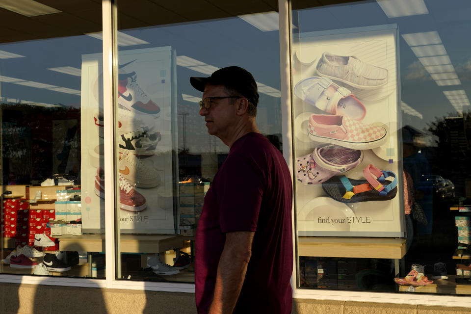 A shopper walks past a storefront window at an outlet mall in Rehoboth Beach, Del., Saturday, June 4, 2022. President Joe Biden faces a delicate trade-off as he tries to help his fellow Democrats in the upcoming midterm elections. He needs U.S. consumers to pull back just enough so that inflation eases, but not so much that the economy risks plunging into a recession. (AP Photo/Patrick Semansky)